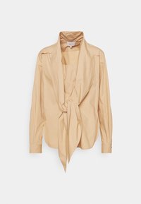 Chemisier long à manches beige clair avec un large col et un détail de nœud à l'avant, exposé sur un fond blanc.
