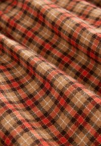 Braun-orange Karo-Stoff mit weicher Textur und kontrastierenden Linien, die ein klassisches Karomuster darstellen.