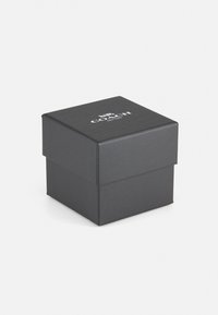Boîte en carton noir avec une finition texturée, portant un logo sur le devant, conçue pour contenir de petits objets ou des cadeaux.