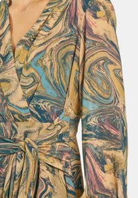 Sukienka w stylu wrap z gładkiego, wzorzystego materiału z wirującymi wzorami niebieskiego, złotego i różowego koloru, z związanym w talii pasem i długimi rękawami.