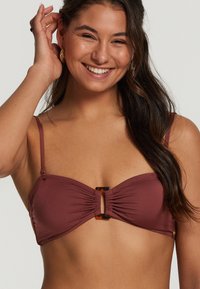 Bramuļa bikinija tops ar savelkušu audumu, regulējamām siksnām un centrālo atslēgvienu ar bruņurupuču akcentiem.