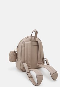 Sac à dos en simili cuir beige de forme arrondie, avec des bretelles réglables et une petite pochette amovible agrémentée de accents en métal doré.