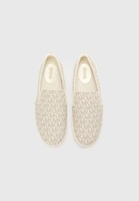 Beige slip-on shoes with textured fabric featuring a repeating MK logo pattern, rounded toe, and a smooth, lightly cushioned insole.