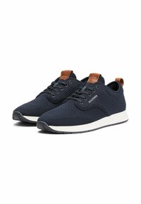 Zapatillas de malla azul marino con una media suela blanca, detalles en cuero marrón en el talón y la lengüeta, presentando una superficie texturizada y un diseño de cordones.