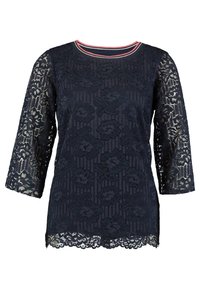 Top in pizzo blu navy con maniche a trequarti, motivo floreale, corpo solido e colletto a strisce rosse e bianche. Dettagli in pizzo testurizzato in tutto il capo.