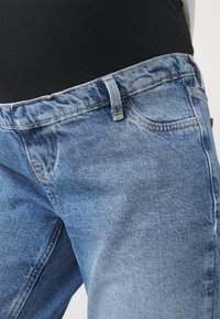 Ljusblå denimjeans med rak front, knappstängning, fem fickor och synliga söm detaljer. Materialet verkar något texturerat.