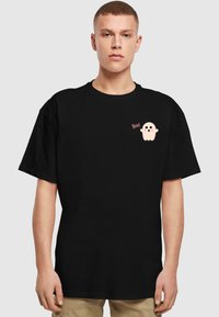 Sort kortærmet t-shirt med et lille pink sp�øgelsesgrafik og ordet "Boo!" trykt på venstre bryst.