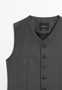 Szary kamizelka z dekoltem w kształcie litery V, z sześcioma czarnymi guzikami z przodu i dwiema bocznymi kieszeniami. Wykonana z teksturowanej tkaniny o dopasowanym kroju.