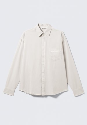 Long-sleeve beige button-up shirt with collar and chest pocket featuring subtle "ATHLETIX DEPT" embroidery.