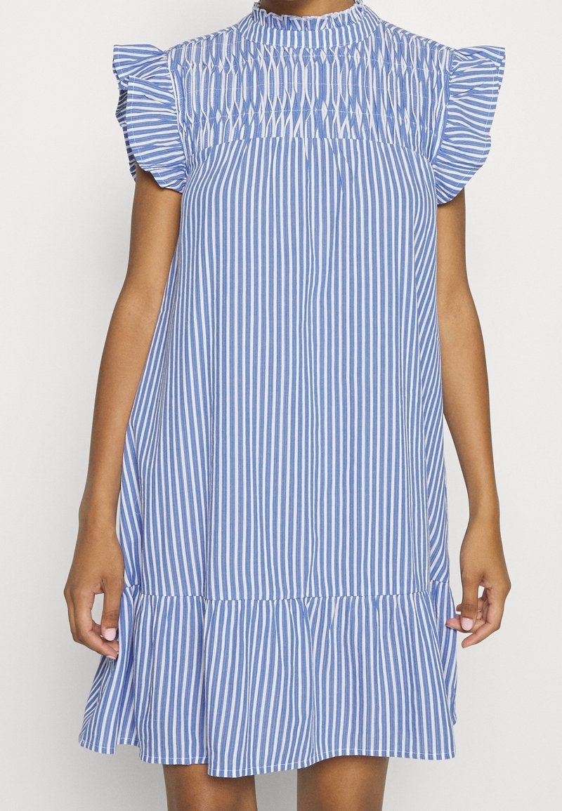 Robe à rayures bleues et blanches avec un col montant, un corsage froncé et des manches à volants. Longueur genoux avec un ourlet évasé. Tissu en coton.