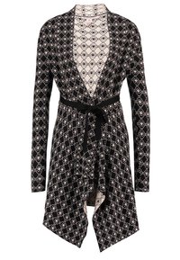 Svartvit mönstrad långärmad kofta med öppen front, asymmetrisk nederkant och ett svart bälte knutet i midjan.