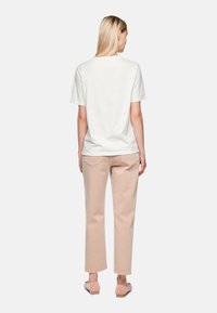 White short-sleeve t-shirt paired with light pink straight-leg pants. The outfit features a simple design with a relaxed fit.