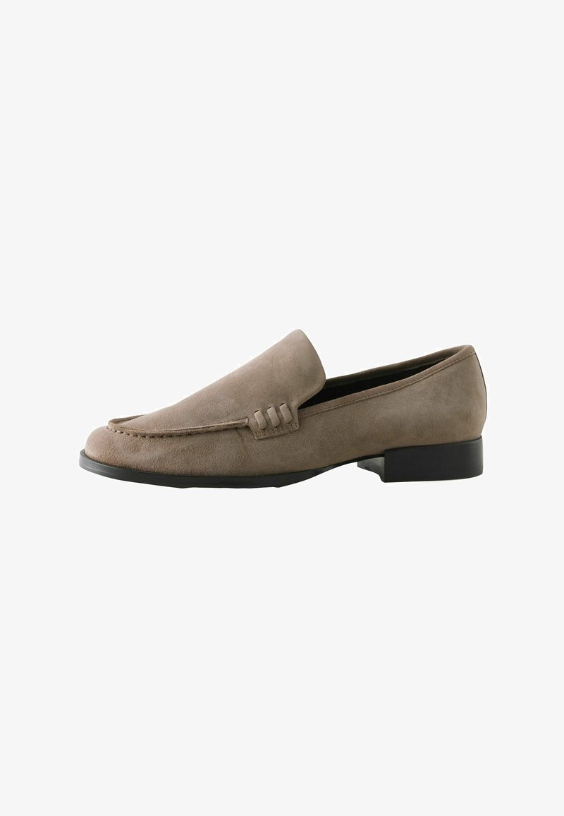Mocassins en daim beige avec une texture lisse, présentant un détail de couture et une semelle noire basse. Design simple et classique à enfiler.