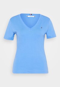 Světle modré tričko s výstřihem do V vyrobené z bavlněné směsi, krátké rukávy, decentní logo na hrudi, hladká textura, přiléhavý střih.