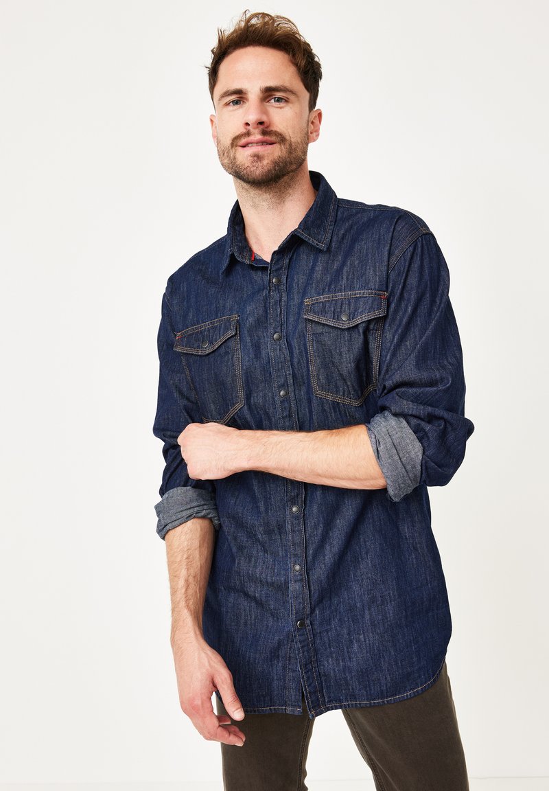 Dunkelblaue Denim-Hemd mit langen Ärmeln, zwei Brusttaschen und Knopfverschluss. Mit hochgerollten Ärmeln und Kontrastnähten.