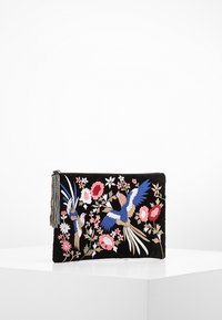 Czarna saszetka na zamek błyskawiczny z kolorowymi haftowanymi ptakami, różowymi kwiatami oraz koralikowym chwostem z boku, wyeksponowana na białej powierzchni.