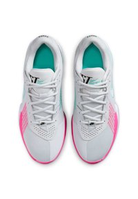 Baskets de sport blanches avec une tige en mesh, dotées d'accents turquoise et d'un panneau latéral rose. Comprend un logo Nike noir et des lacets.
