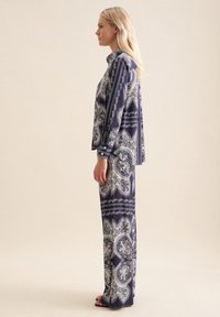 Set due pezzi blu navy stampato, composto da una camicia a maniche lunghe con bottoni e pantaloni a gamba larga con fantasie e dettagli bianchi a paisley.