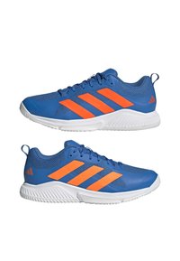 Chaussures de sport bleues avec des rayures orange vif et des semelles blanches, vues de côté et en angle.