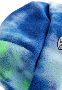 Blå fleecehat med en gradientmønster i lys blå, mørk blå og en anelse grøn. Har et rundt logo-patch på siden.