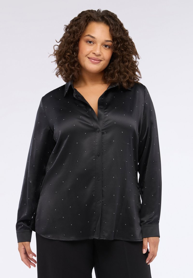 Camisa de satén negro de manga larga con botones en la parte delantera, que presenta pequeñas tachuelas plateadas dispuestas en un patrón disperso por toda la tela.