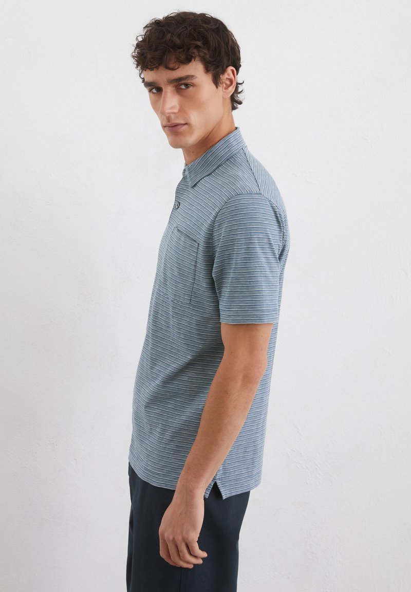 Gestreiftes Kurzarm-Polohemd in Hellblau und Marineblau, mit Button-Down-Kragen und Fronttasche, aus einem leichten Stoff gefertigt.