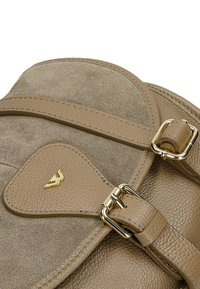 Kabelka z tanového kůže a semiše s promyšleným designem, zlatými kovovými detaily a texturovaným povrchem s zaobleným klopovým víkem.