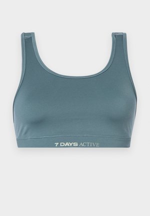 Sportowy stanik w ciemnym odcieniu teal, wykonany z miękkiego, elastycznego materiału. Posiada okrągły dekolt oraz elastyczny pas z napisem "7 DAYS ACTIVE" w jasnym kolorze.