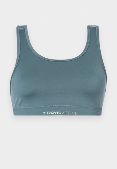 Sport bra in dark teal, made of soft, stretchy fabric. Features a scoop neckline and elastic band with "7 DAYS ACTIVE" printed in light color.