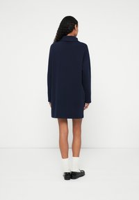 Robe ample bleu marine en matière douce, dotée de manches longues et d'un col plié. Design simple et droit avec une longueur à mi-cuisse.