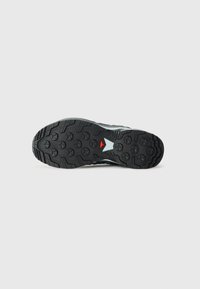 Talpa de pantof sport cu un design texturat din cauciuc negru, având un accent alb și roșu. Profilul include modele circulare și unghiulare pentru aderență.