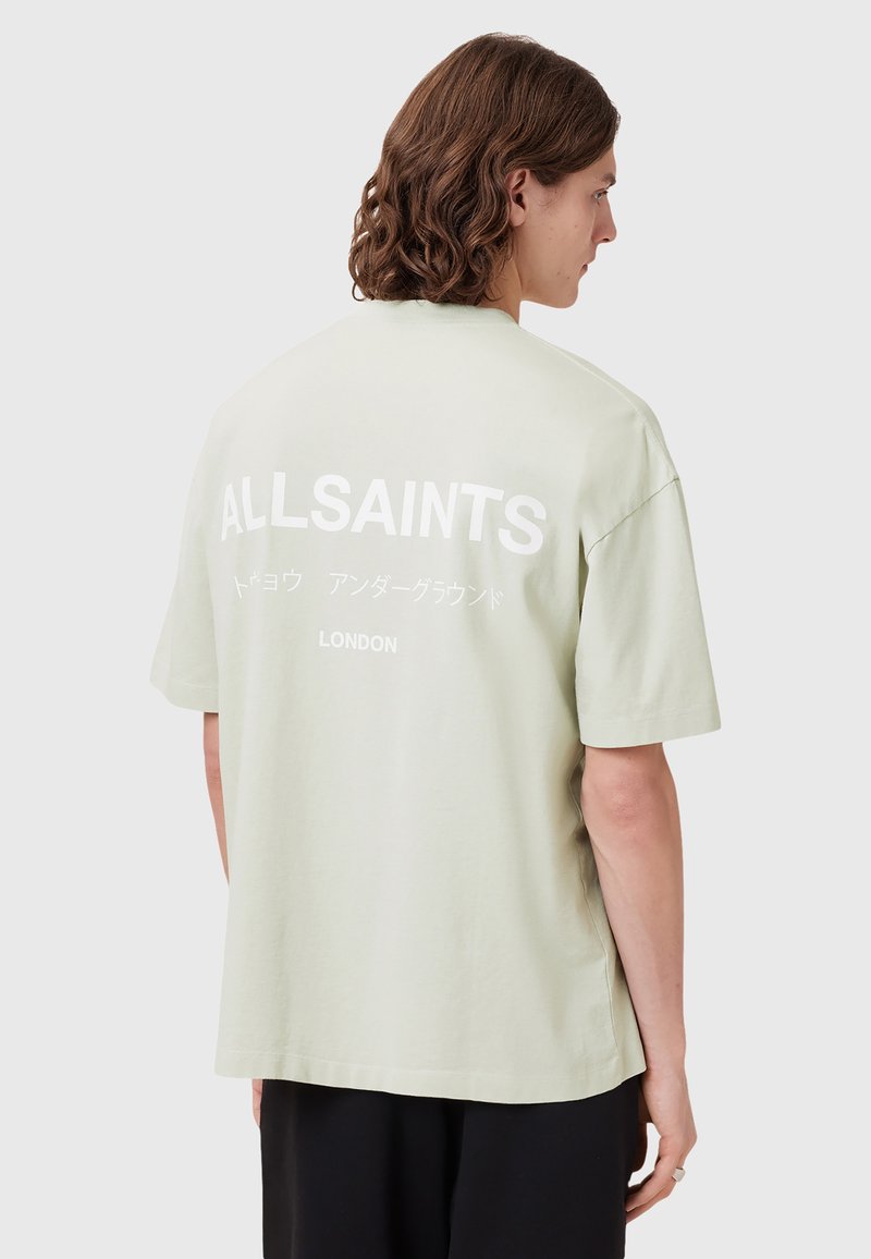 Šviesiai žalia per didelė medvilninė marškinė su apvaliu iškirpimu. Nugaros pusėje yra dideli balti užrašai "ALLSAINTS LONDON."