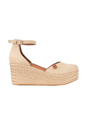 Sandalias de cuña de ante beige con plataforma de yute trenzado y correa en el tobillo. Presenta una punta redondeada y un pequeño acento de logo marrón en la parte superior.