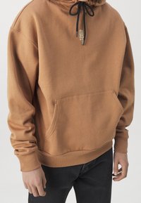 Sudadera de color marrón con capucha, hecha de una tela suave, con un bolsillo frontal, capucha ajustable con cordón y puños y bajo acanalados. Diseño simple y casual.