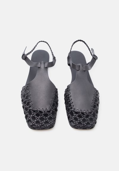 Μαύρα δερμάτινα σανδάλια με πλεγμένα λουράκια, τετράγωνη μύτη και υφαντές λεπτομέρειες στο μπροστινό μέρος, με ρυθμιζόμενες αγκράφες στον αστράγαλο.