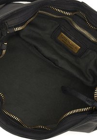 Interno di una borsa in pelle nera con cerniera dorata, foderato in tessuto e con etichetta del marchio. Testura liscia, forma circolare e senza caratteristiche esterne visibili.