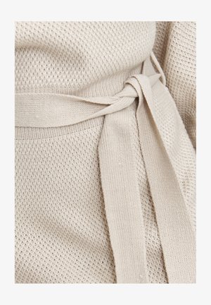 Beżowy dziany element odzieży z teksturowanym wzorem, z paskiem w talii i gładkim wykończeniem na brzegach.