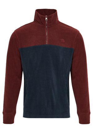 Fleece-Pullover mit einem Halbmantel-Reißverschluss, der einen burgunderfarbenen oberen Bereich und einen navyblauen unteren Abschnitt hat. Weiche Textur mit einem Logo auf der Brust und gerippten Bündchen.