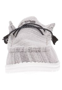 Scarpa atletica grigia lavorata a maglia con lacci neri, punta arrotondata e tomaia strutturata. Presenta una suola bianca e un design minimalista.