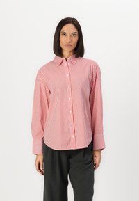 Camicia a righe rossa e bianca con colletto, maniche lunghe e polsini larghi; tessuto liscio e vestibilità comoda.