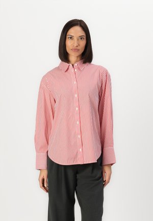 Chemise à boutons rayée rouge et blanche avec col, manches longues et larges poignets ; tissu lisse et coupe décontractée.