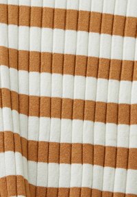 Gros plan sur un tissu tricoté côtelé avec des rayures horizontales alternées en blanc et marron clair.