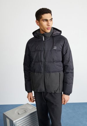 Black puffer jacket with a hood, featuring a front zipper and elastic cuffs. Two-tone design, with a smooth texture and branded logo.