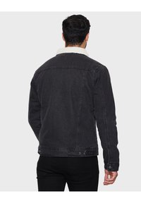 Zwarte denim jas met een sherpa kraag, aansluitend ontwerp en knoopmanchetten. Zichtbare stikseldetails en zijzakken.