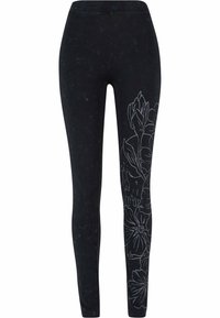 Sorte leggings med blomstertrykk i hvitt langs siden, laget av mykt materiale med en glatt tekstur og en tettsittende design.
