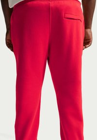 Rode sweatpants van zachte stof, voorzien van een enkele achterzak en een elastische tailleband. Soepele textuur met een comfortabele pasvorm.