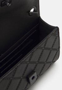 Černá kožená peněženka s prošívaným vzorem, elegantního obdélníkového tvaru, s několika přihrádkami na karty a zapínáním na patentku.