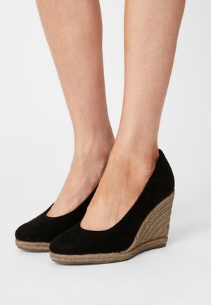 Des chaussures à talons compensés en daim noir avec un bout rond et un talon en jute tressé. La hauteur du talon est d'environ 7 cm.