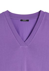 T-shirt z dekoltem w serek w jednolitym fioletowym kolorze, charakteryzujący się gładką fakturą i krótkimi rękawami. Metka widoczna na dekolcie.