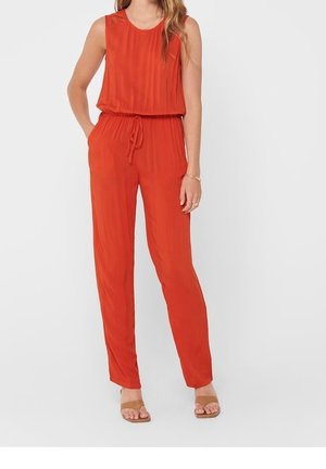 Czerwony bezrękawnik kombinezon z talią ściągniętą sznurkiem. Wykonany z lekkiego materiału z delikatnymi pionowymi paskami. Dopełnieniem stylizacji są płaskie sandały.